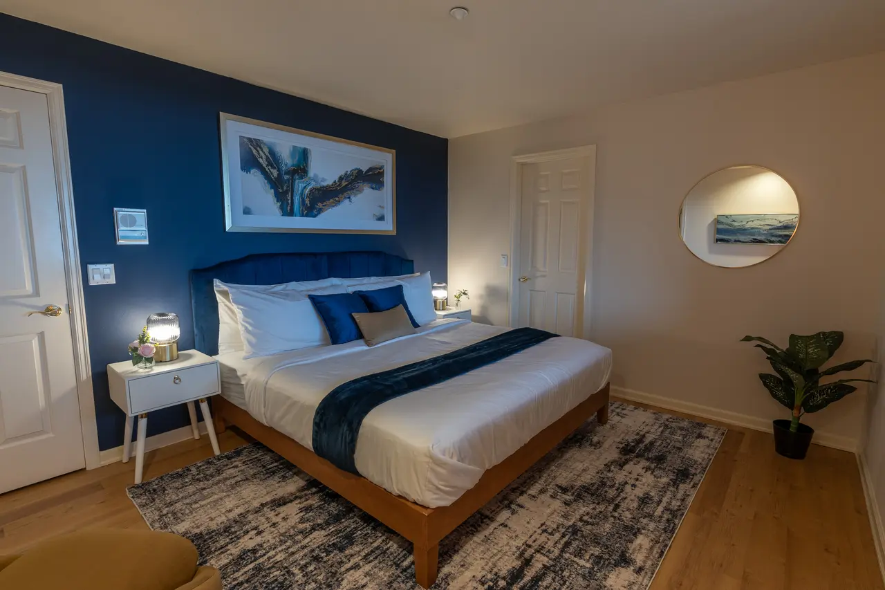 Third King bedroom featuring a deep blue  'Azure' accent wall with giant art and plush bed.